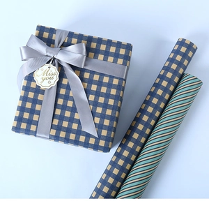 Close-up of blue plaid kraft paper gift box with grey ribbon and matching paper rolls