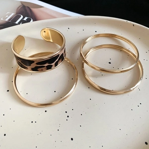 Detailed view of leopard print cuff bracelet and gold bangles set on ceramic tray