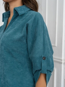 Detail showing the peacock blue corduroy fabric texture and buttoned cuff of the dress