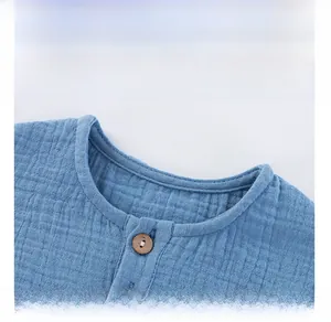 Detail view of cotton gauze fabric and wooden buttons on blue baby lounge set top