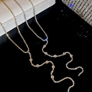 Detail of silver and gold rhinestone tassel necklaces with large circular crystals on black mirror