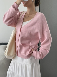 Detail of pink V-neck knit cardigan with functional buttons and front pocket design