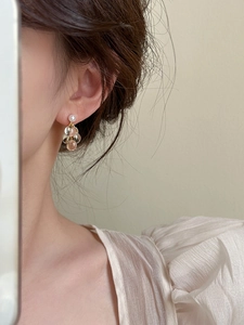 Détail de boucles d'oreilles grappes en résine avec perles champagne sur chaîne dorée