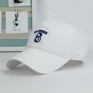 Detail of white cotton baseball cap featuring dark blue 'THE NUMBER 6' embroidery