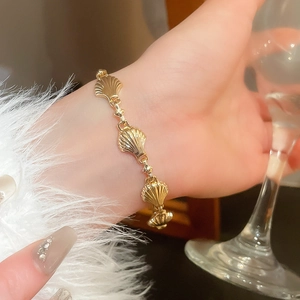 Detailed view of a gold shell-shaped bracelet on a wrist with an elegant lifestyle vibe
