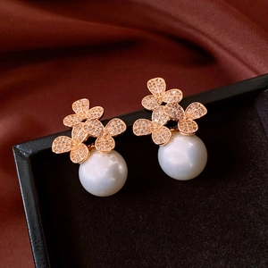 Makroaufnahme von Roségold-Ohrringen mit Zirkon-Blumen und eleganten weißen Perlen