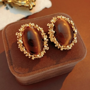 Macro shot of vintage tiger eye stone earrings with molten gold texture on a velvet box