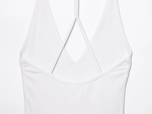 Detailed close-up of white halter neck cross straps and fine knit fabric of the mini dress