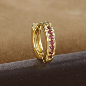 Macro view of gold huggie earring with row of pink zircon stones on textured leather