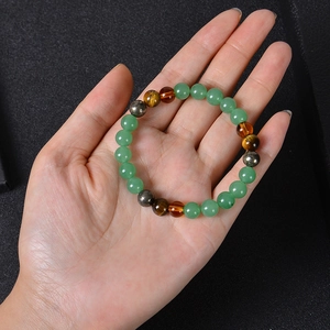 Natural tiger eye and turquoise beaded wealth bracelet held in hand against dark background
