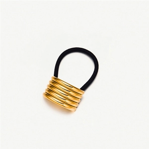 Detail of golden stainless steel spiral hair coil with black elastic band for ponytail