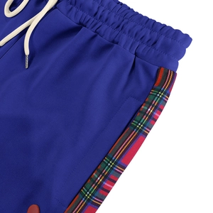 Detail of blue joggers featuring plaid side stripes and elastic waist with white drawstrings