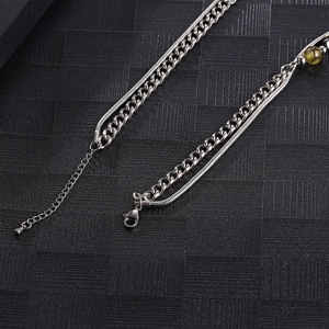 Detail of silver snake chain and Cuban link necklace with green stone bead accent