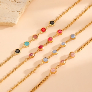 Stack of gold plated stainless steel bracelets with colorful gemstone charms in various hues