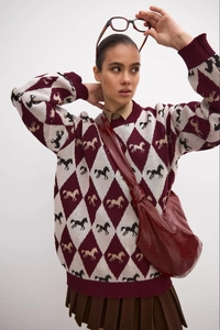 Detailed knit texture of burgundy argyle sweater featuring horse jacquard patterns