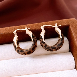 Détail macro de boucles d'oreilles créoles rétro imprimé léopard avec attaches dorées