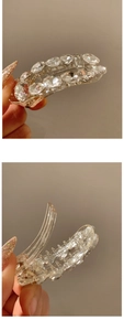 Close-up of a clear hair claw clip featuring sparkling rhinestones and crystal stones