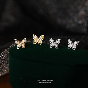 Macro shot of silver and gold butterfly studs on a green velvet box with S999 silver logo