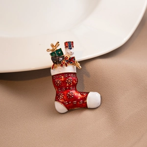 Macro detail of Christmas stocking brooch with red and green enamel on metal