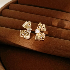 Détail macro de boucles d'oreilles nœuds dorés avec texture évidée et zircons brillants