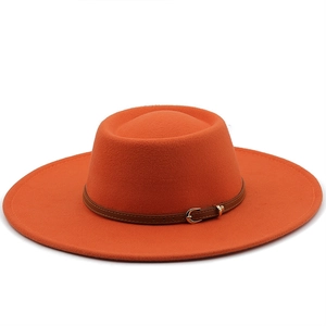 Detailed close-up of the orange wool felt fedora featuring a brown leather belt buckle strap