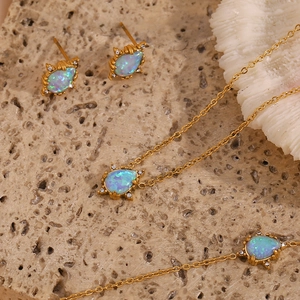 Macro detail of gold plated jewelry set featuring teardrop opal stones and crystals