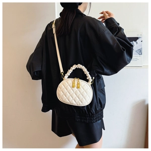 Stylish white quilted crossbody bag with unique ruffled handle and gold zippers.