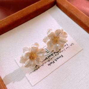 Macro view of French floral earrings with pearlescent petals and golden stamens detail