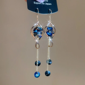 Dettaglio macro di orecchini geometrici argentati con frange di cristallo blu lucido