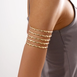 Detail of multi-layered gold arm cuff with wavy hammered texture on a model's arm