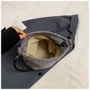 Detail view of large gray knit bucket bag showing beige lining and inner zipper pocket