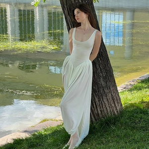 Detail of elegant white backless maxi dress with a side slit on a model in sunlight