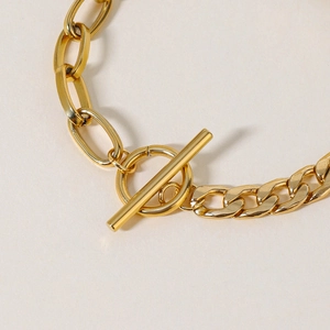 Detail of gold titanium bracelet featuring mixed chain links and a heart toggle clasp