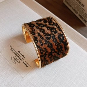 Détail du bracelet manchette ouvert avec imprimé léopard et bordure en métal doré poli