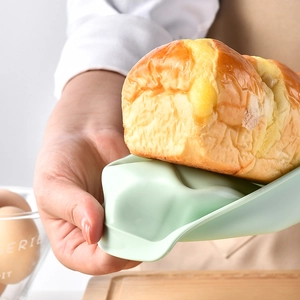 Silicone loaf pan for baking with fresh golden bread on a light green tray