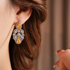 Close-up of luxury silver flower earring with yellow drop-shaped zircon on a model's ear