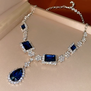 Close-up of blue square and teardrop crystal pendant necklace in a jewelry box
