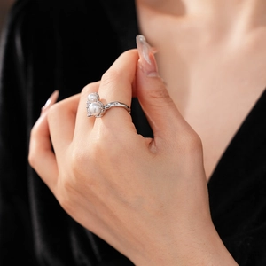Détail d'une bague argentée avec deux perles blanches et texture de métal martelé