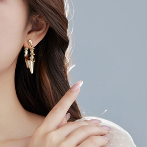 Macro shot of geometric gold earrings with micro-inlaid rhinestones on a female model