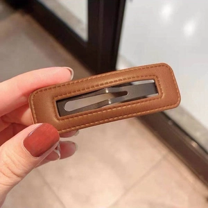 Detailed close-up of brown textured leather hair clip with handcrafted stitching