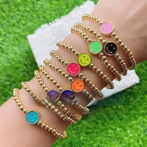 Close-up of gold beaded stretch bracelets featuring colorful enamel smiley face charms