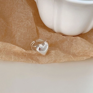 Detail of silver heart-shaped open ring displayed on textured craft paper background