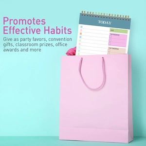 Pink spiral daily planner in a gift bag showing sections for habits and priorities