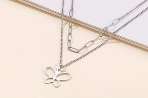Detail of a silver double-layer necklace with a paperclip chain and hollow butterfly charm