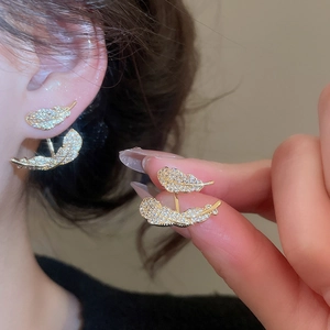 Macro view of gold plated feather earrings featuring sparkling cubic zirconia stones