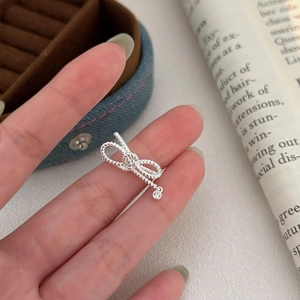 Detailed shot of a sterling silver bow ring featuring rope texture and a zircon pendant