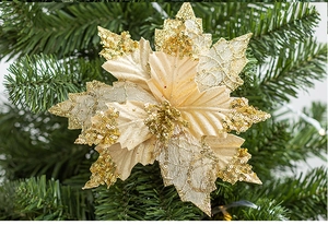 Détail d'un poinsettia artificiel doré à paillettes sur une branche de sapin de Noël