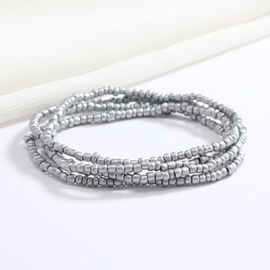 Macro shot of layered silver metal beads jewelry on beige fabric background