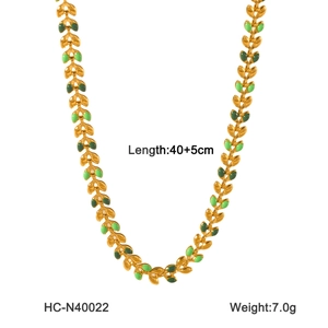 Détail du collier en acier inoxydable doré avec motif de feuille d'olivier en émail vert