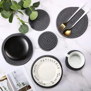 Flat lay of gray woven cotton rope placemats and coasters on marble surface